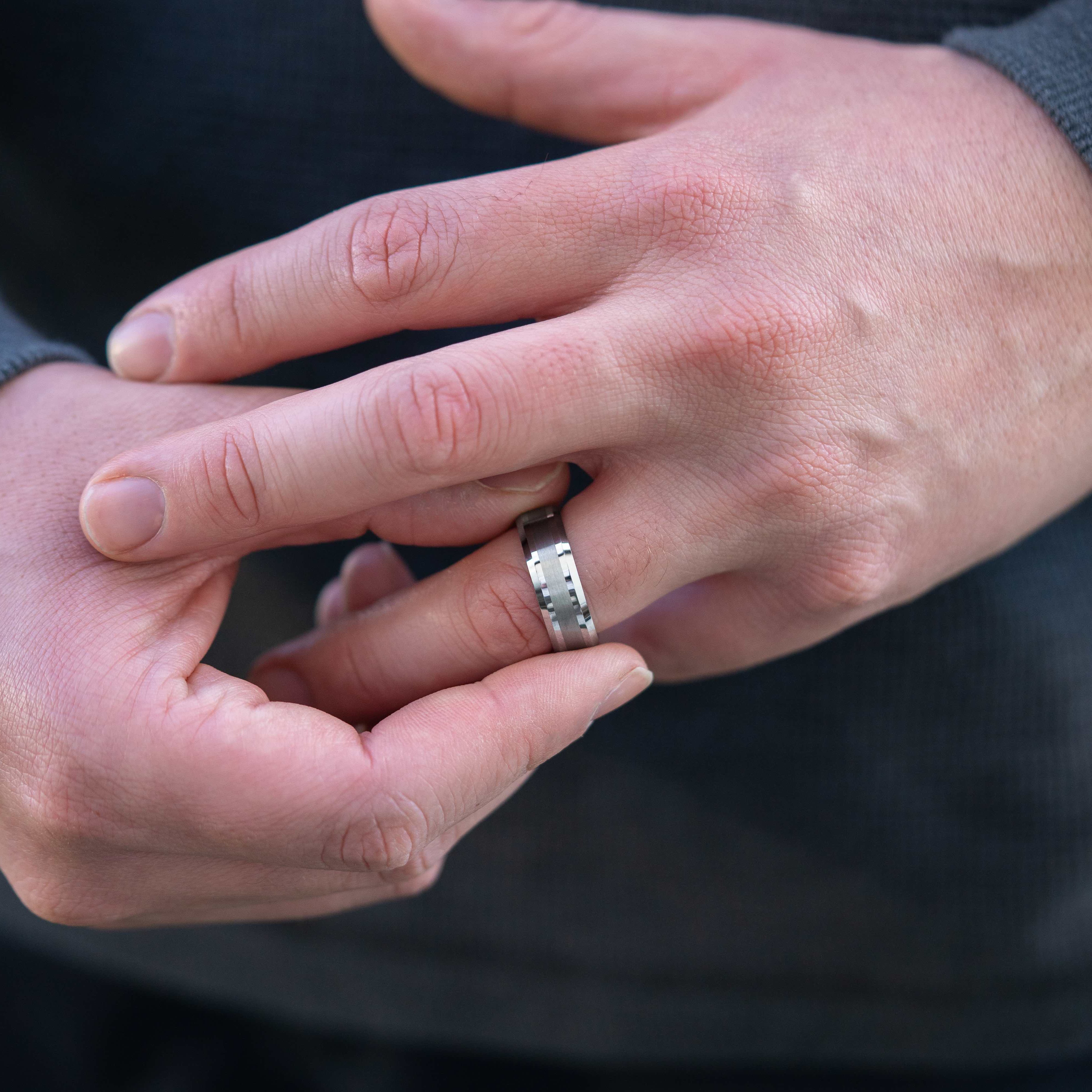 Closeup of a man wearing the "The Navigator" silver tungsten ring with a brushed and polished finish adjusting the ring on his finger