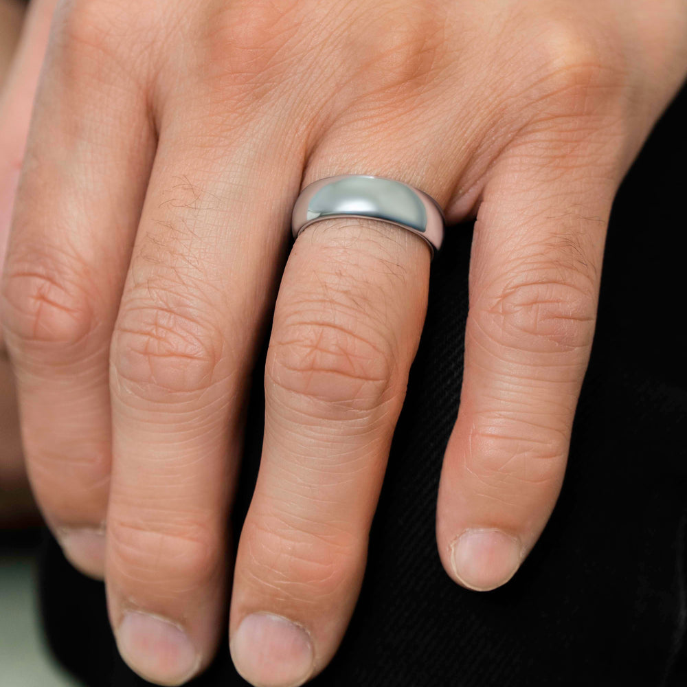 Closeup of a man wearing "The Maverick" tungsten ring in polished silver wearing blue pants and resting his hand on his knee