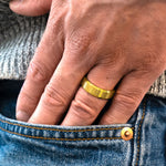 Closeup of a man wearing "The Vintage" tungsten ring in brushed gold putting his hand into the pocket of his blue jeans